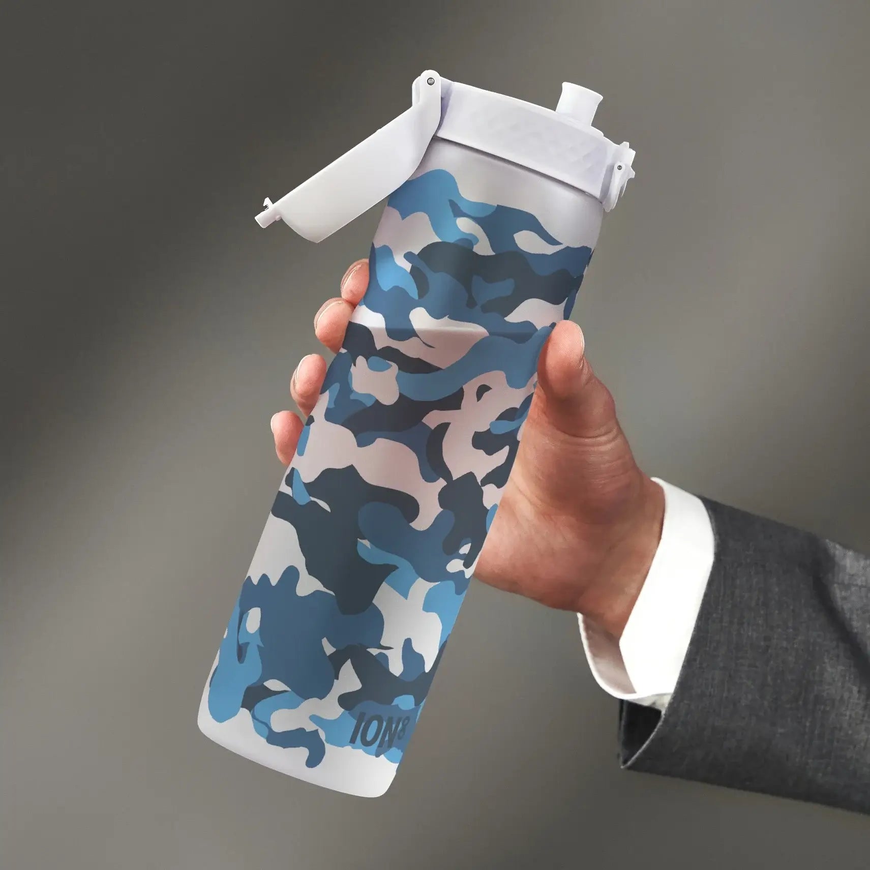 A blue camouflage water bottle is held by a person wearing a suit. The bottle has a white lid and the word “ION8” is visible near the bottom.