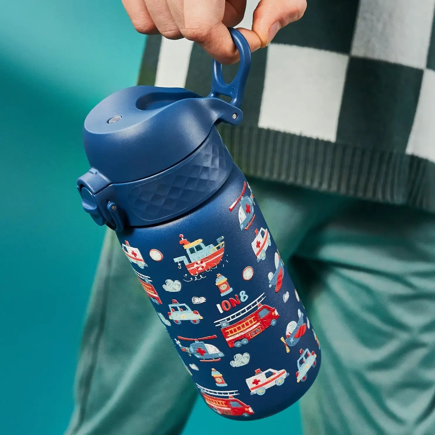 A blue water bottle, featuring a child-like illustration of emergency vehicles, is held by a person against a teal backdrop. ION8 is visible on the bottle.